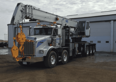 A large crane with a yellow bucket, positioned prominently against a clear sky, showcasing its industrial capabilities.